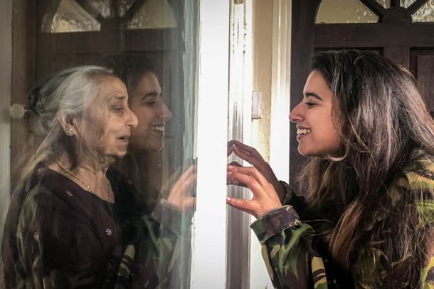 Srečanje babice in vnukinje skozi okensko steklo