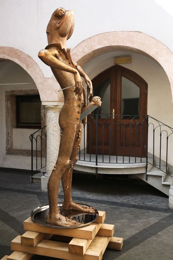 Pompozni pokončni bronasti žabec v fraku, ki asociira na moški spolni organ, je Bratuševa subtilna kritika galerijskega establišmenta. 