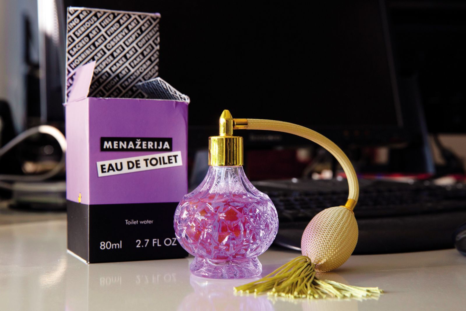 Umetniško delo Eau de Toilet Iris Pokovec je dejansko toaletna voda, saj je kičasta steklenička parfuma napolnjena z vodo iz stranišča.