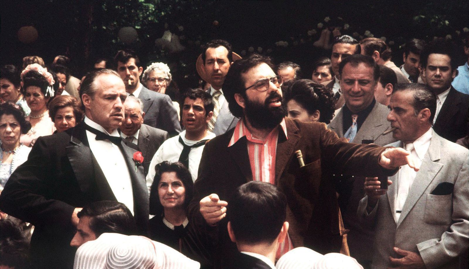 Režiser Francis Ford Coppola (v sredini z brado) daje navodila Marlonu Brandu (levo) in drugim članom ekipe na snemanju filma Boter (1972)