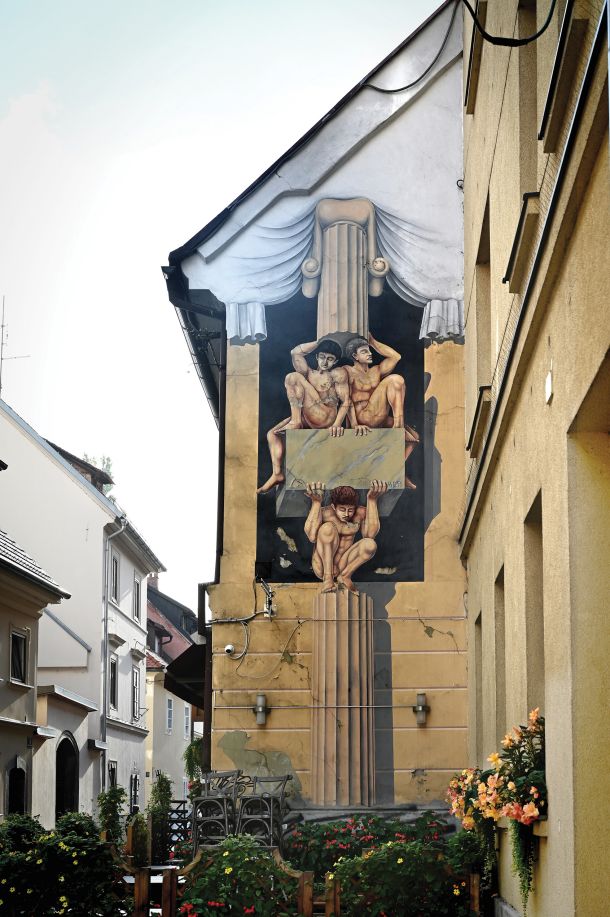 Manjša slepa fasada ob Pizzeriji Foculus v Ljubljani je popestrena z manjšo, z renesančno iluzionistiko navdihnjeno poslikavo.
