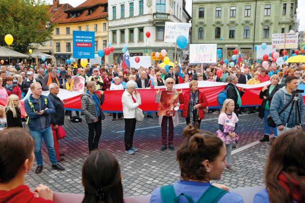 Tisočglava množica, ozaljšana z barvitimi baloni, slovenskimi zastavami in transparenti, ki nasprotuje splavu. 