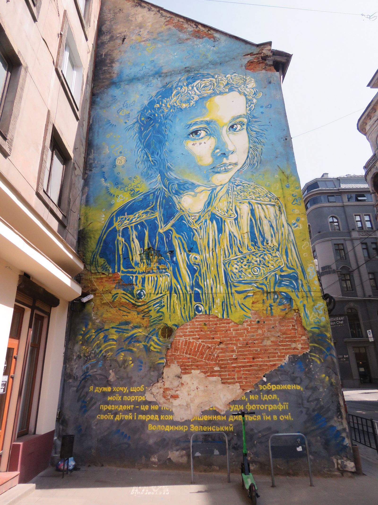 Mural z delom govora ob zaprisegi ukrajinskega predsednika Zelenskega leta 2019: Ukrajince je prosil, naj prekinejo s tradicijo izobešanja portretov predsednikov in na stene raje namestijo slike otrok ter jim pred sprejetjem vsake odločitve pogledajo v oči. Fotografirano v Lvovu.