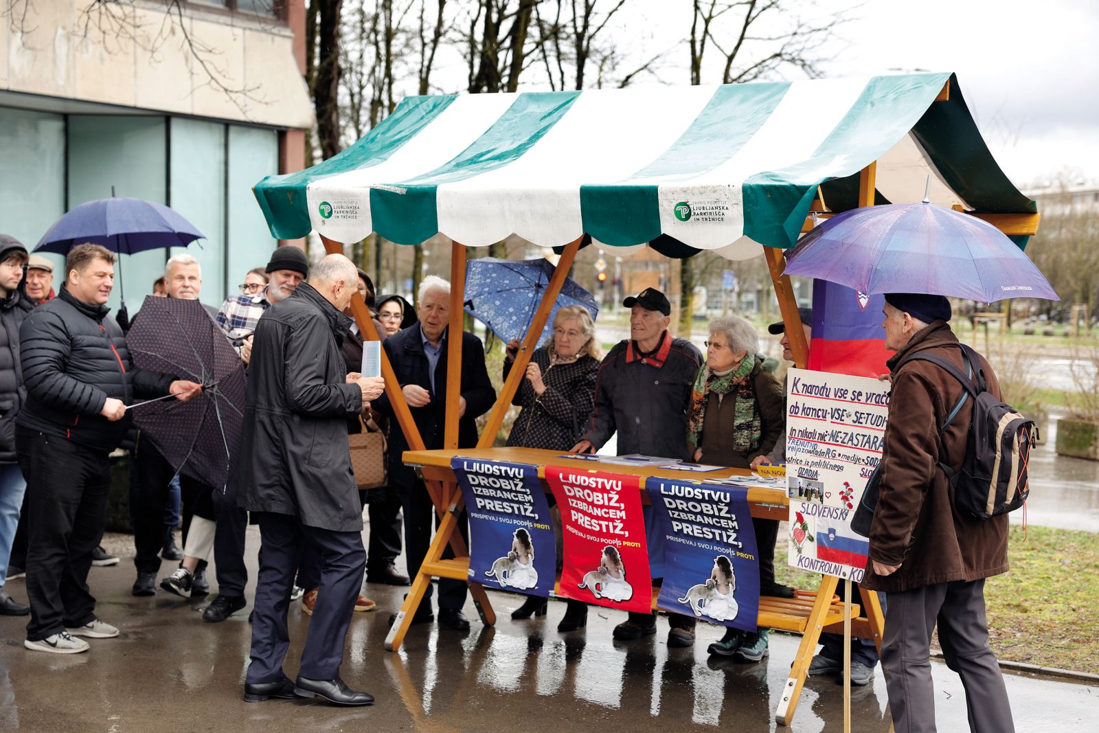 Janez Janša in njegovi strankarski podporniki ob stojnici s spornimi plakati