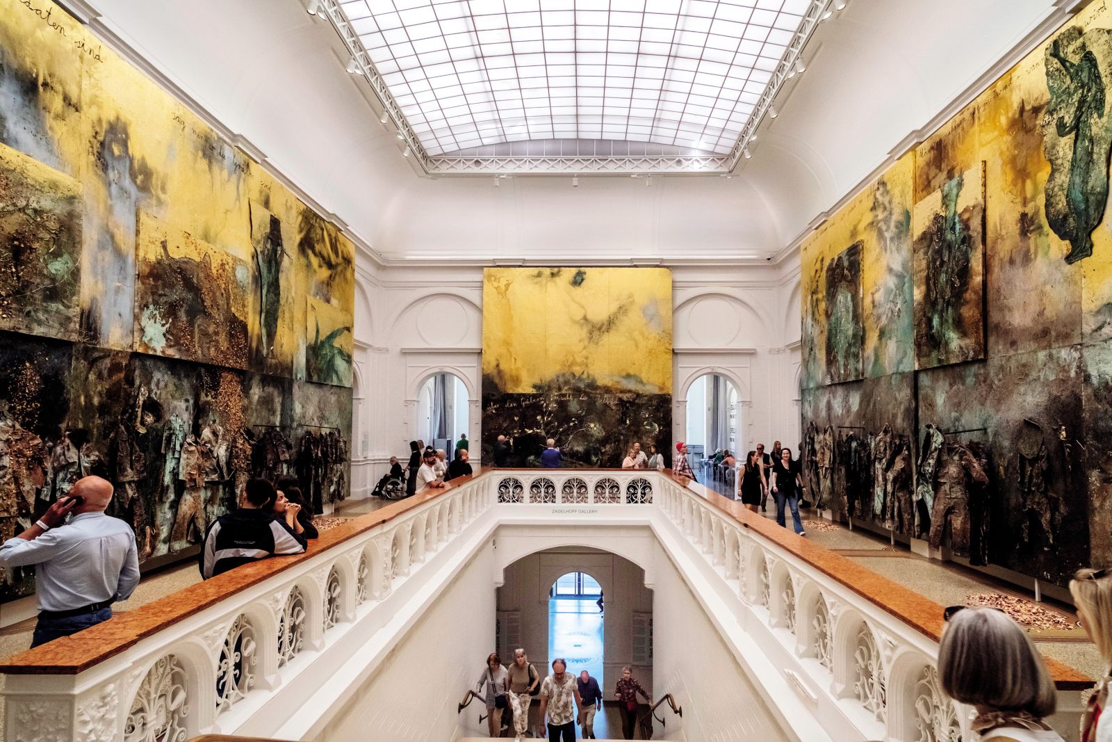 Na razstavi Anselma Kieferja v muzeju Stedelijk tudi njegovo najnovejše delo (2024), ki je hkrati osrednje, monumentalno, saj zavzame celotno stopnišče muzeja, opozarja na vojne, nasilje in temne plati človeške nravi: spodnji deli ustvarjajo občutek nelagodja in strašljivosti, zgornje figure pa so umeščene v pozlato, simbol (ne)doseženega ideala.