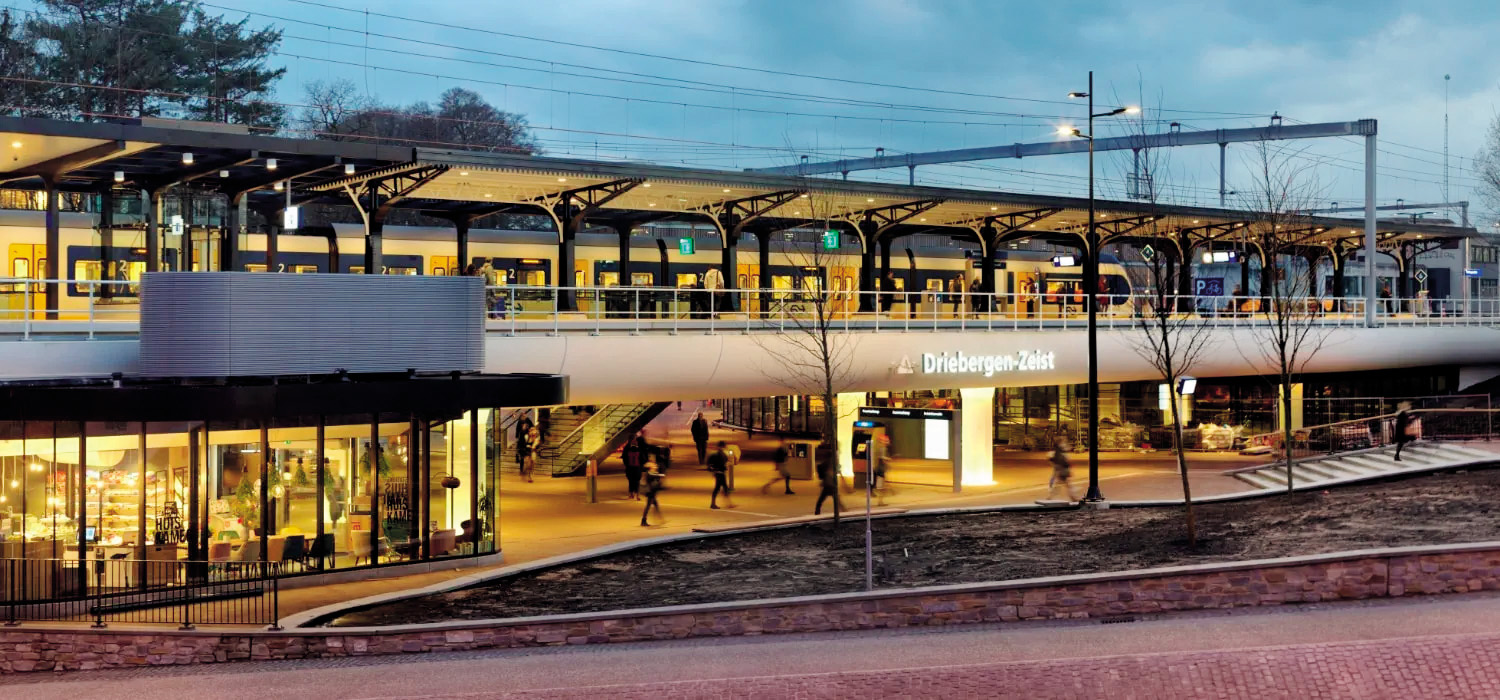 Prenovljena železniška postaja v nizozemskem somestju Driebergen-Zeist, ki je s sodobno avtobusno postajo in krajinskimi ureditvami učinkovito povezana prek širše občinske mreže javnega prevoza.