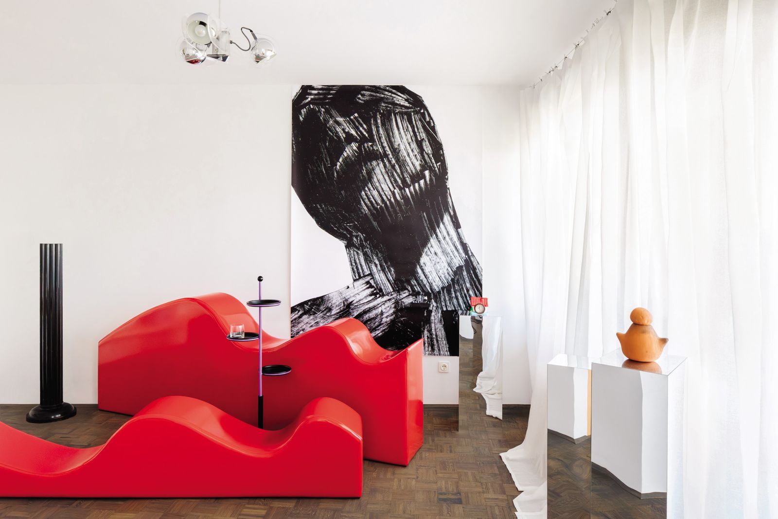 V dnevni sobi stanovanja J50, prenovljenega letos, očara bleščeče rdeči modularni kavč, ki je lahko tudi postelja ali počivalnik.